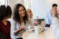 A woman smiling with a laptop and coffee cup