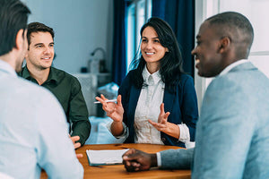 A woman standing at a table speaking to colleagues